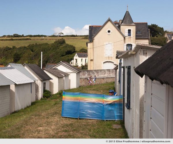Bathing cabins and bathers on a sunny windy summer day on Ris Beach, Douarnenez, France, 2013 by Elise Prudhomme