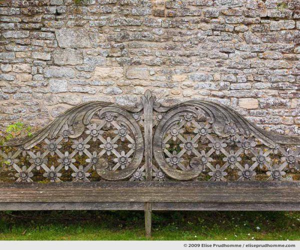 Carved wooden bench and stone wall, Brecy Castle Gardens, Saint Gabriel Brécy, France, 2009 (series Notable Gardens of France) by Elise Prudhomme.