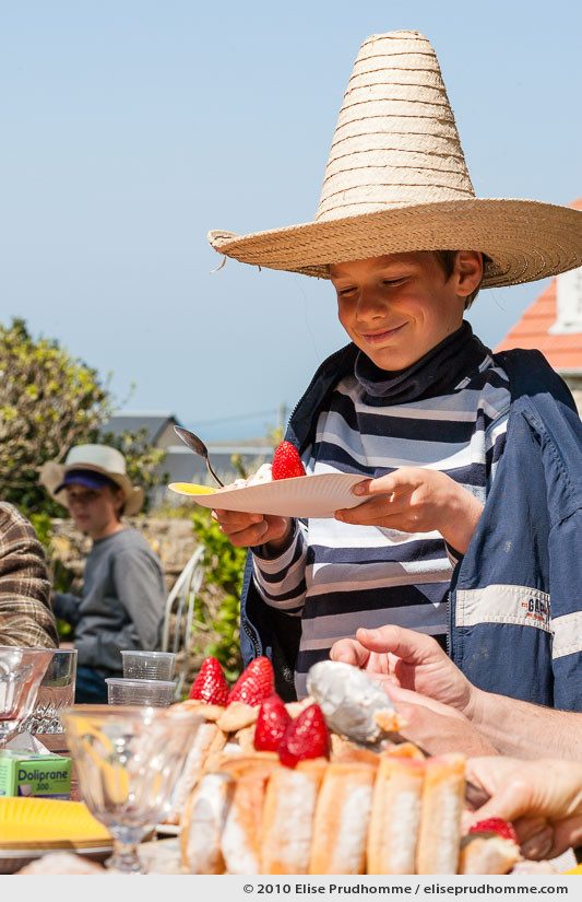 Smiling boy in a sombrero holding a paper plate with Strawberry Charlotte dessert, Normandy, France, 2010 by Elise Prudhomme.