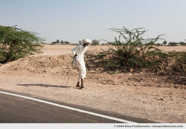 Elderly white-bearded man in traditional Bishnoi clothing walking along the roadside, Rohet, India by Elise Prudhomme.