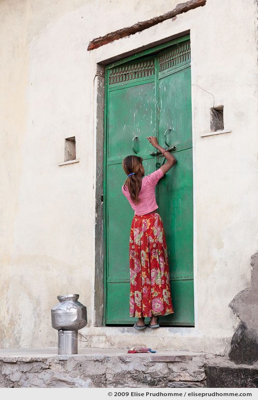 Girl in a rural Indian village latching the door of her home before collecting water from a communal well, Delwara, Rajasthan, Northern India, 2009.
