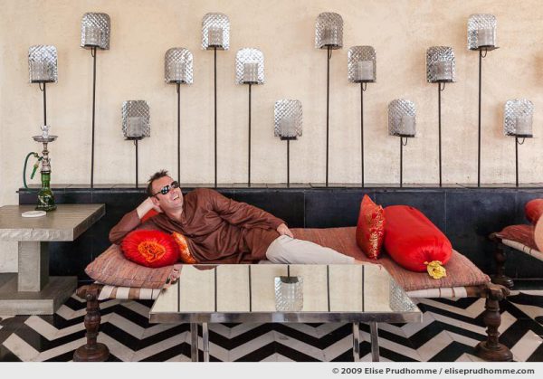 Middle-aged Caucasian man wearing an Indian tunic and sunglasses relaxing on sofa in Devi Garh Resort Hotel, Delwara, India, 2009 by Elise Prudhomme.