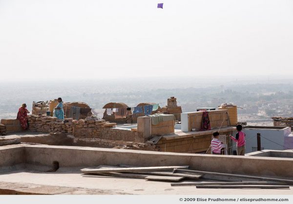 Two boys flying a kite and two women talking on the rooftops of golden city of Jaisalmer, Rajasthan, Western India, 2009 by Elise Prudhomme.