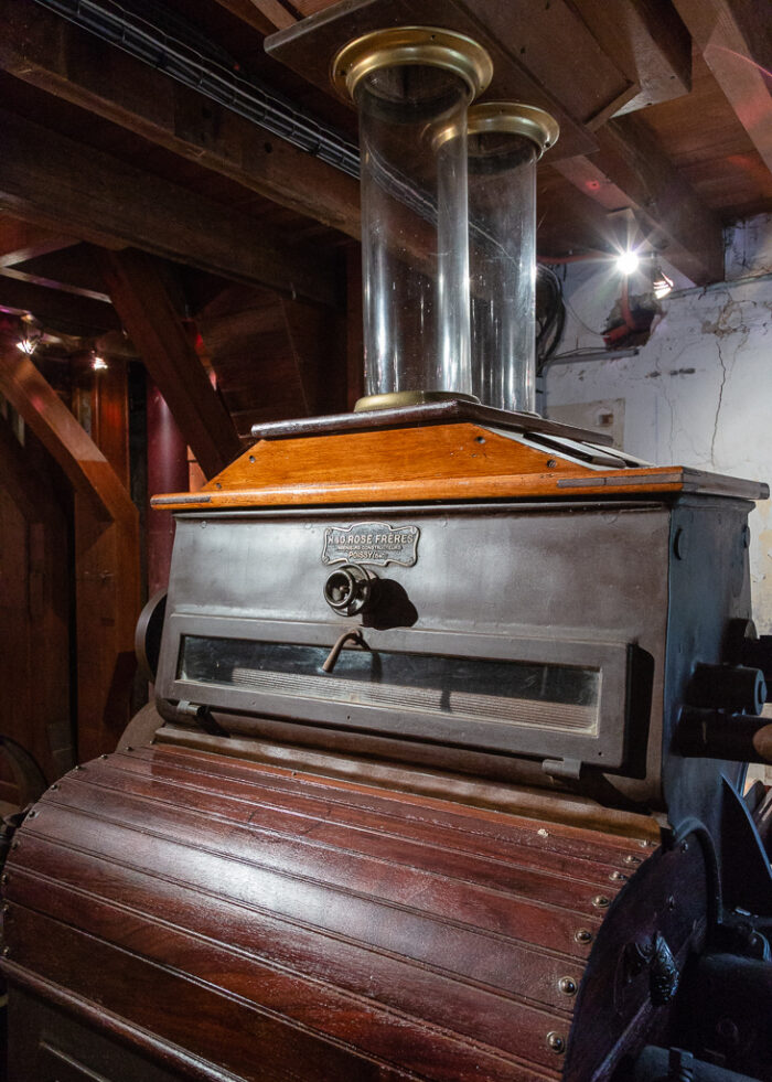 This roller mill, built in the workshops H. & G. Rose brothers of Poissy, is part of the crushing equipment of Saint-Gabriel Flour Mill. Its hull of metal and wood envelops cast iron cylinders that grind wheat grains falling from glass supply globes. Several successive passages between different cylinders are necessary to obtain a white flour.