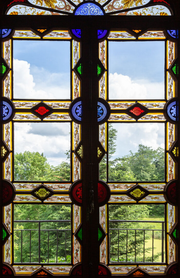 Stained glass window and landscape behind at the Chateau de Maulmont near Vichy, France.